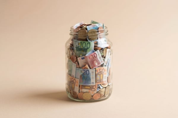 Un gros bocal avec des pieces et des billets